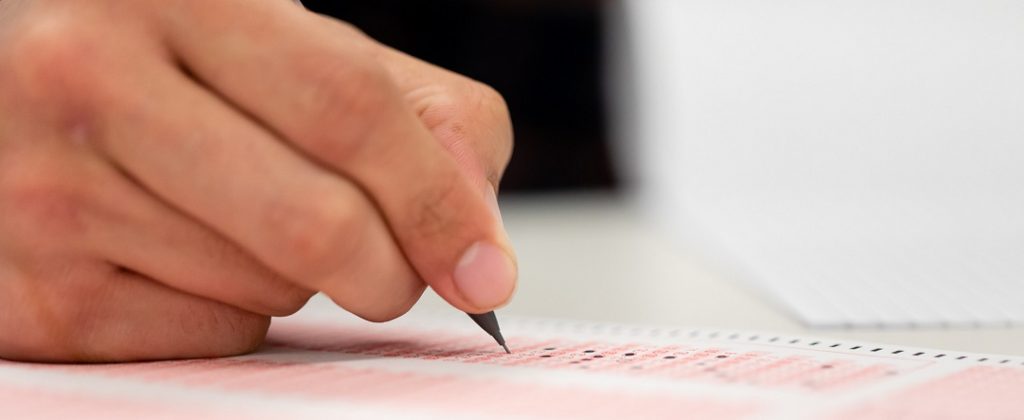 Photograph of a hand filling out a bubble sheet. 