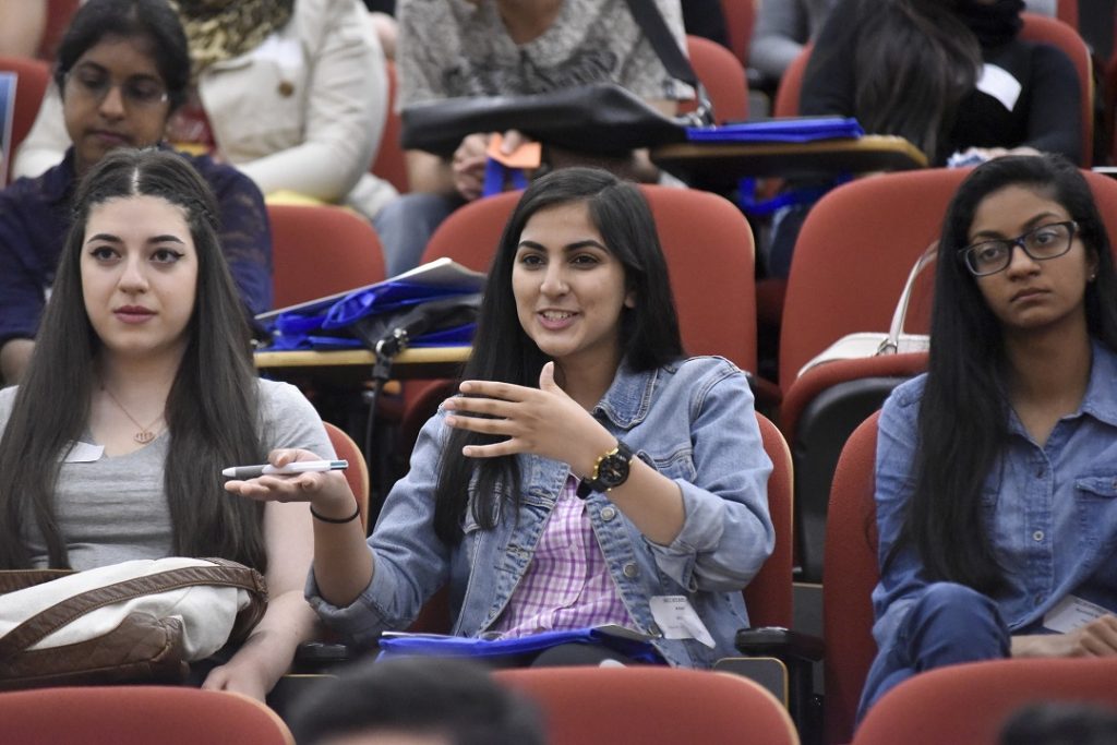 A group of three students sit in a lecture hall. 