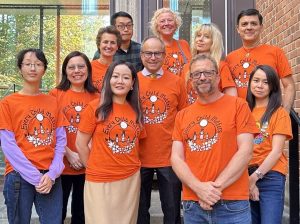 Department of Economics staff in orange shirts with Professor Ettore Damiano, Department Chair