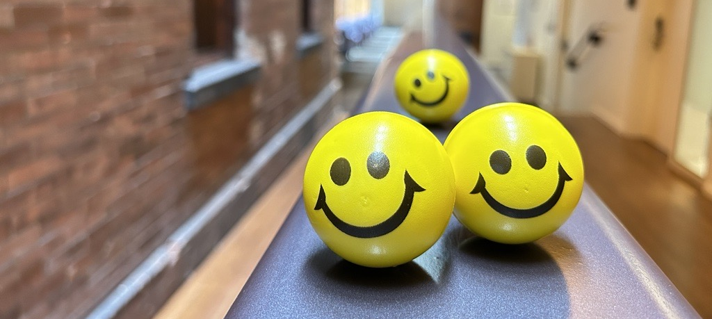 Three smiley face stress balls on the ramp railing at Max Gluskin House